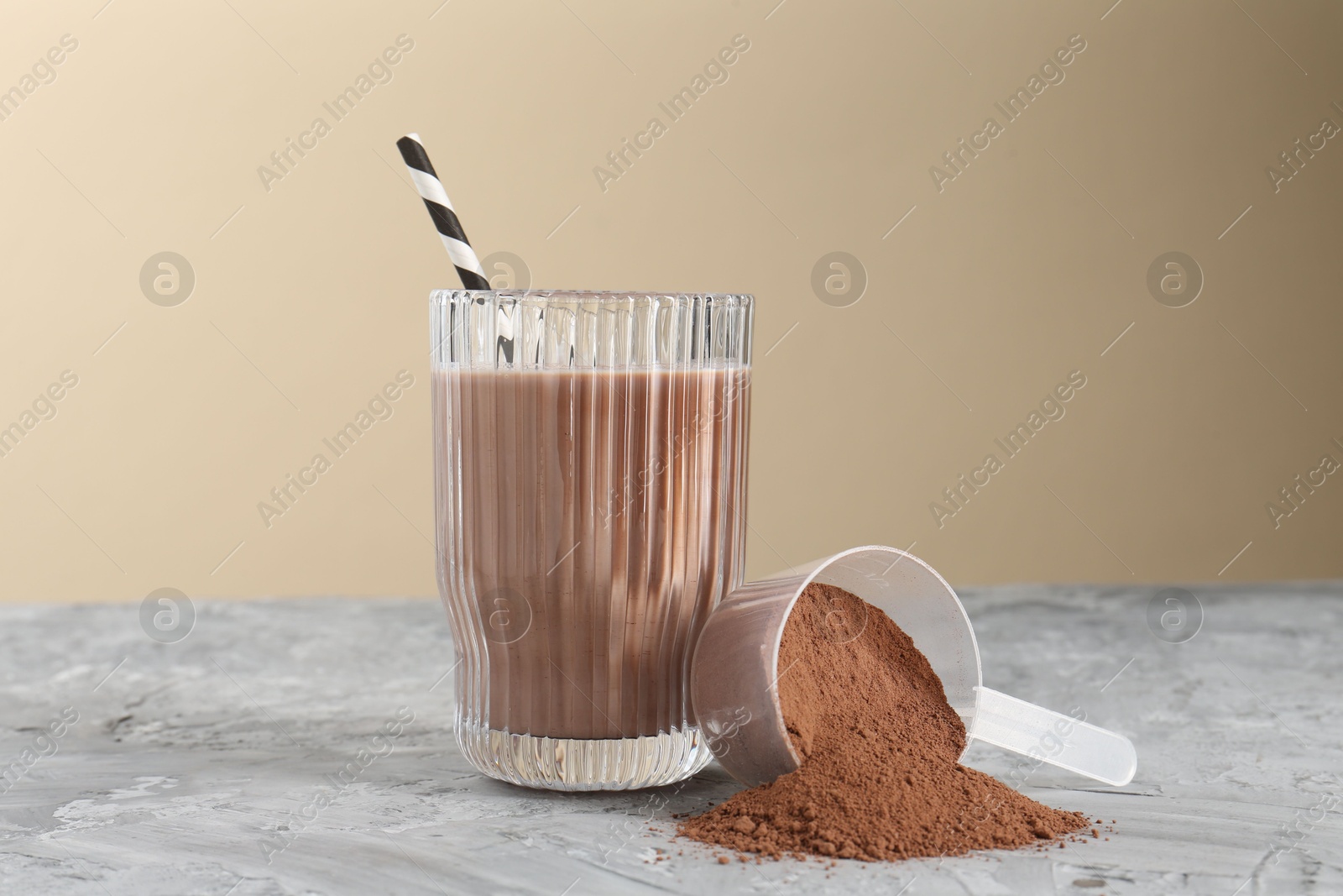 Photo of Delicious protein shake in glass and scoop with powder on grey table