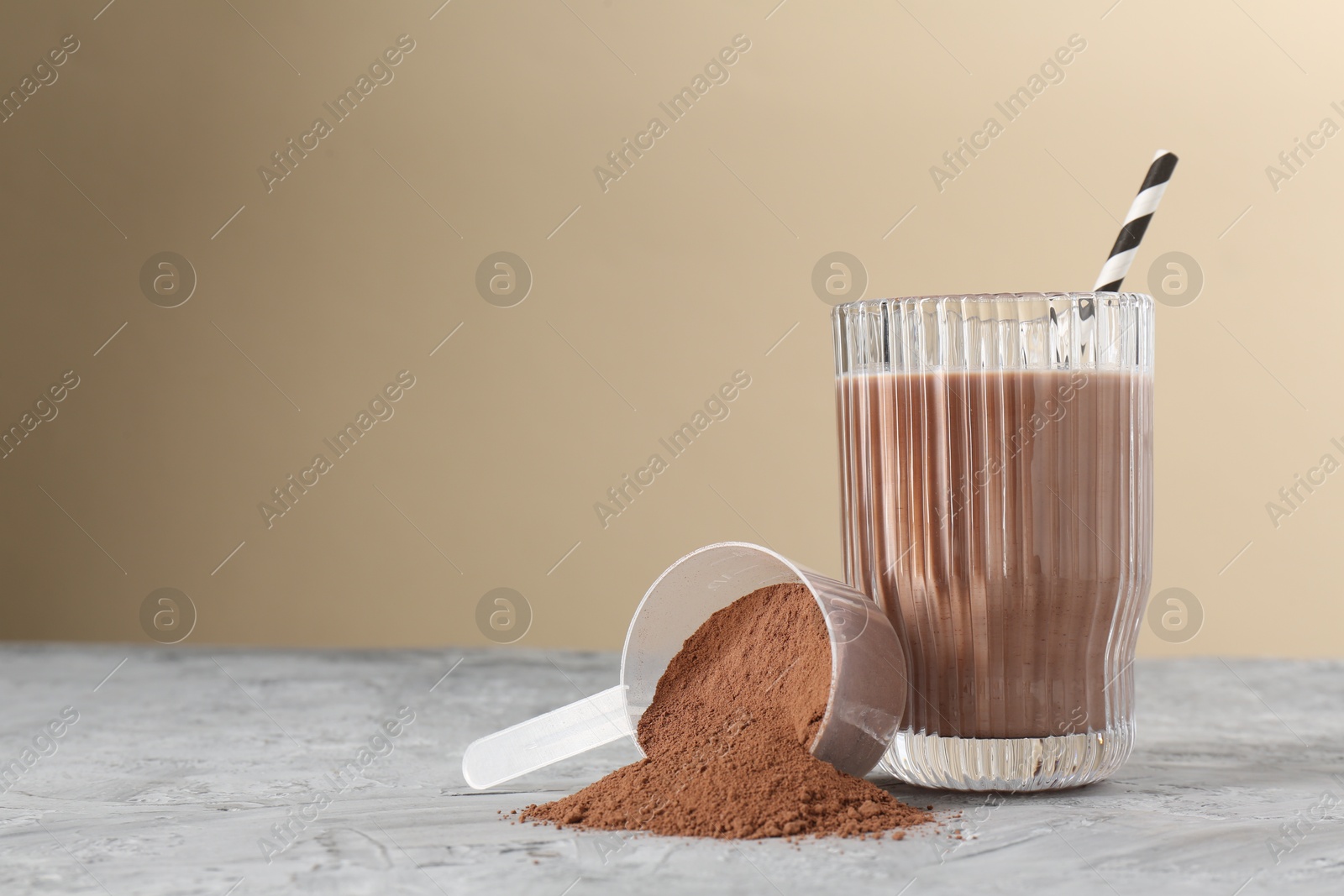 Photo of Delicious protein shake in glass and scoop with powder on grey table, space for text