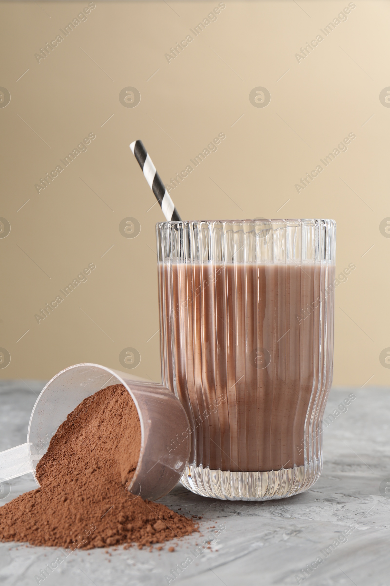 Photo of Delicious protein shake in glass and scoop with powder on grey table