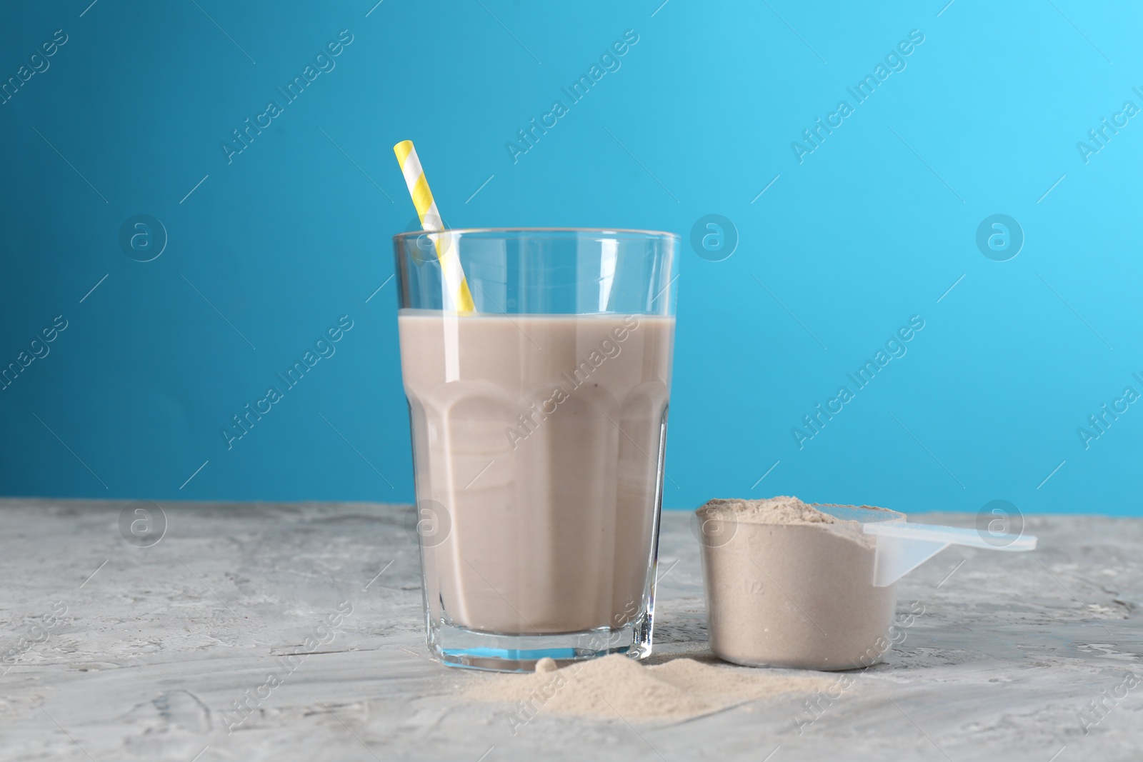 Photo of Delicious protein shake in glass and scoop with powder on grey table