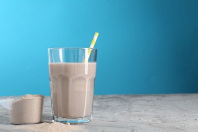 Photo of Delicious protein shake in glass and scoop with powder on grey table, space for text