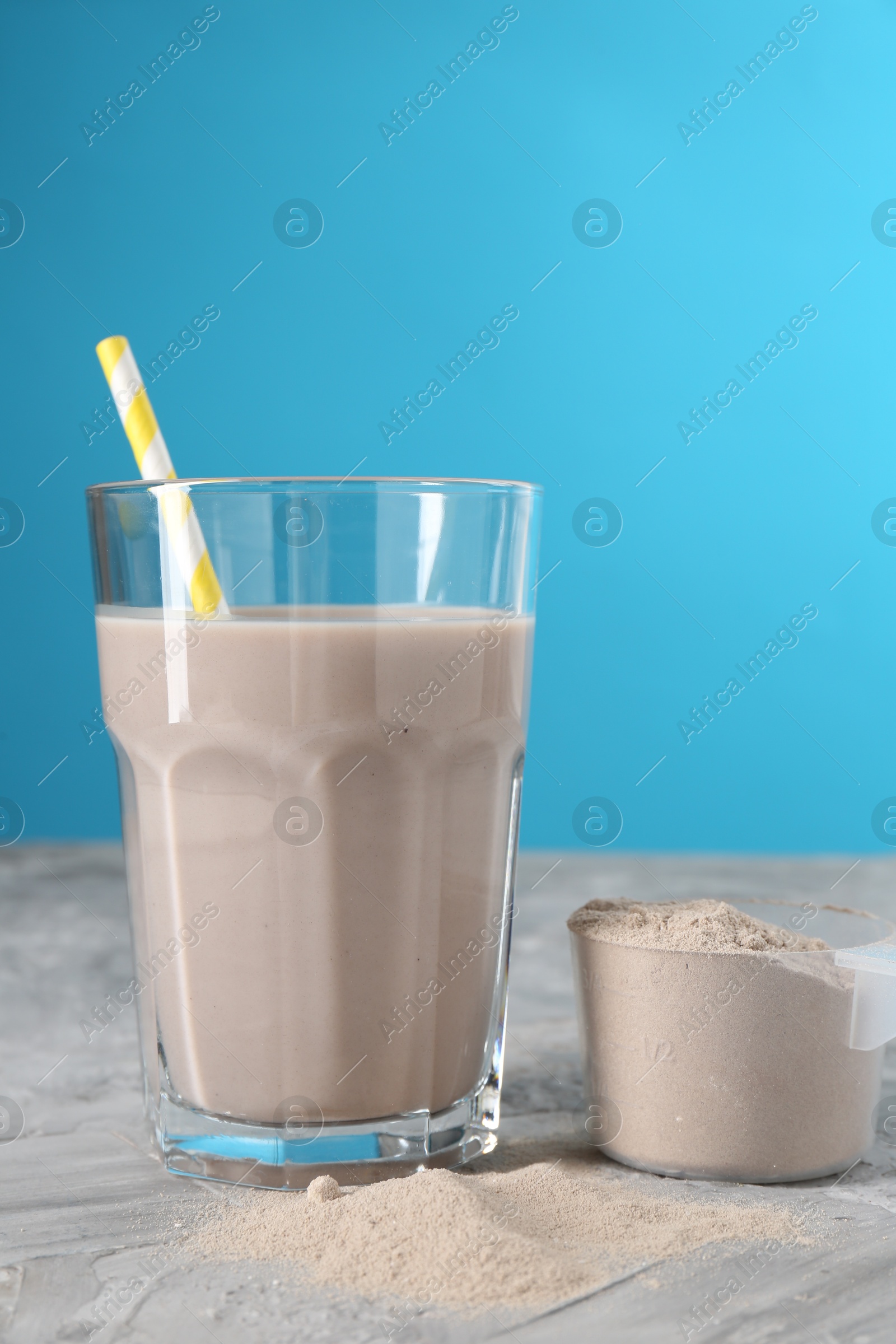 Photo of Delicious protein shake in glass and scoop with powder on grey table