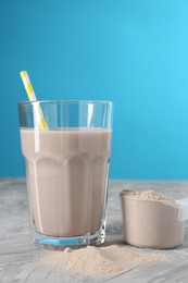 Photo of Delicious protein shake in glass and scoop with powder on grey table