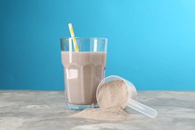 Photo of Delicious protein shake in glass and scoop with powder on grey table