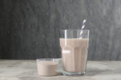 Photo of Delicious protein shake in glass and scoop with powder on grey table