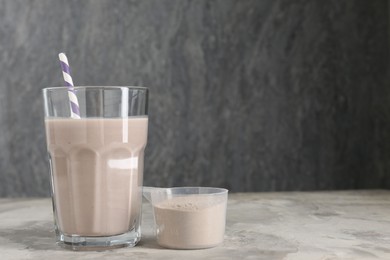 Photo of Delicious protein shake in glass and scoop with powder on grey table, space for text