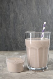 Photo of Delicious protein shake in glass and scoop with powder on grey table