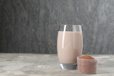 Photo of Delicious protein shake in glass and scoop with powder on grey table, space for text