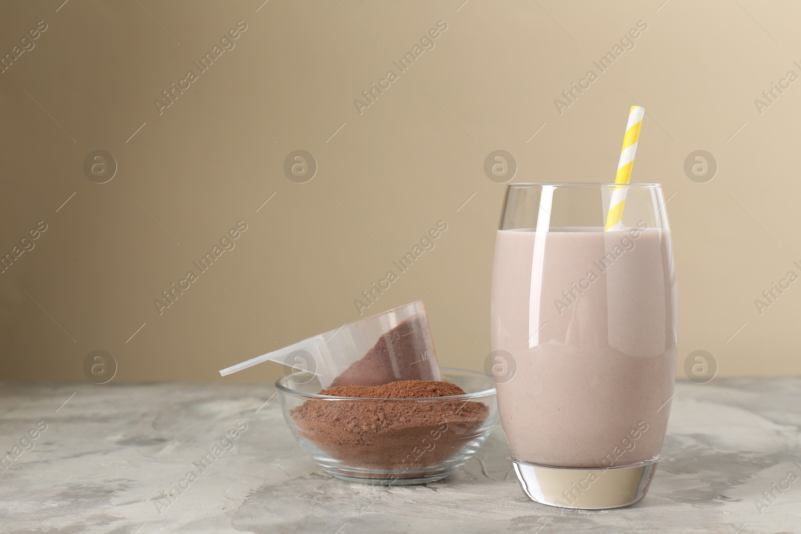 Photo of Delicious protein shake in glass and powder on grey table