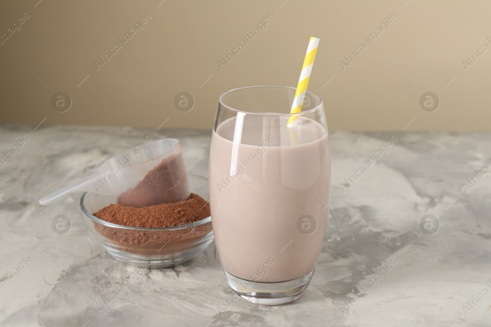 Photo of Delicious protein shake in glass and powder on grey table