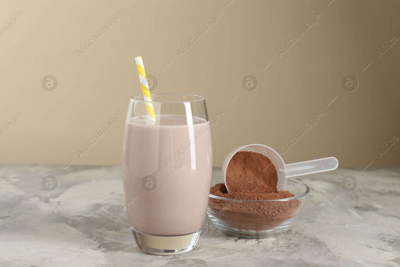 Photo of Delicious protein shake in glass and powder on grey table