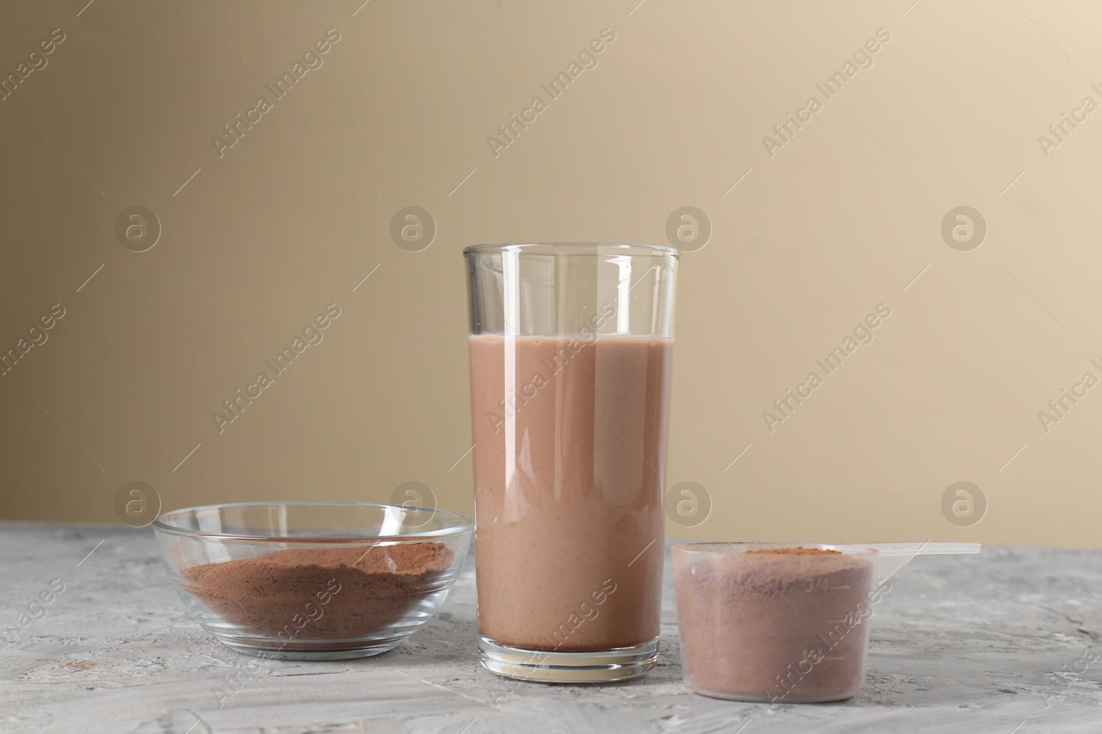 Photo of Delicious protein shake in glass and powder on grey table