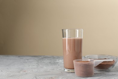 Photo of Delicious protein shake in glass and powder on grey table, space for text