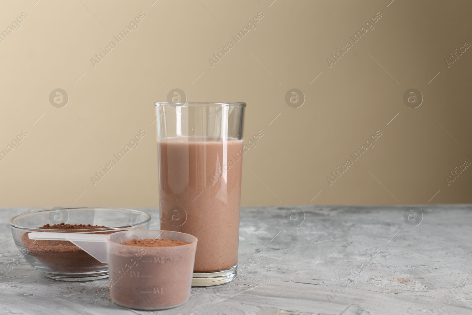 Photo of Delicious protein shake in glass and powder on grey table, space for text