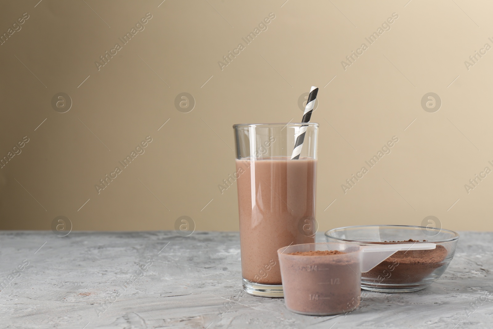 Photo of Delicious protein shake in glass and powder on grey table, space for text