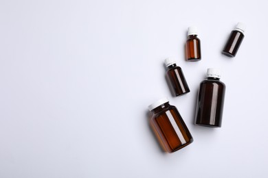 Photo of Medical bottles with medicine on white background, top view. Space for text