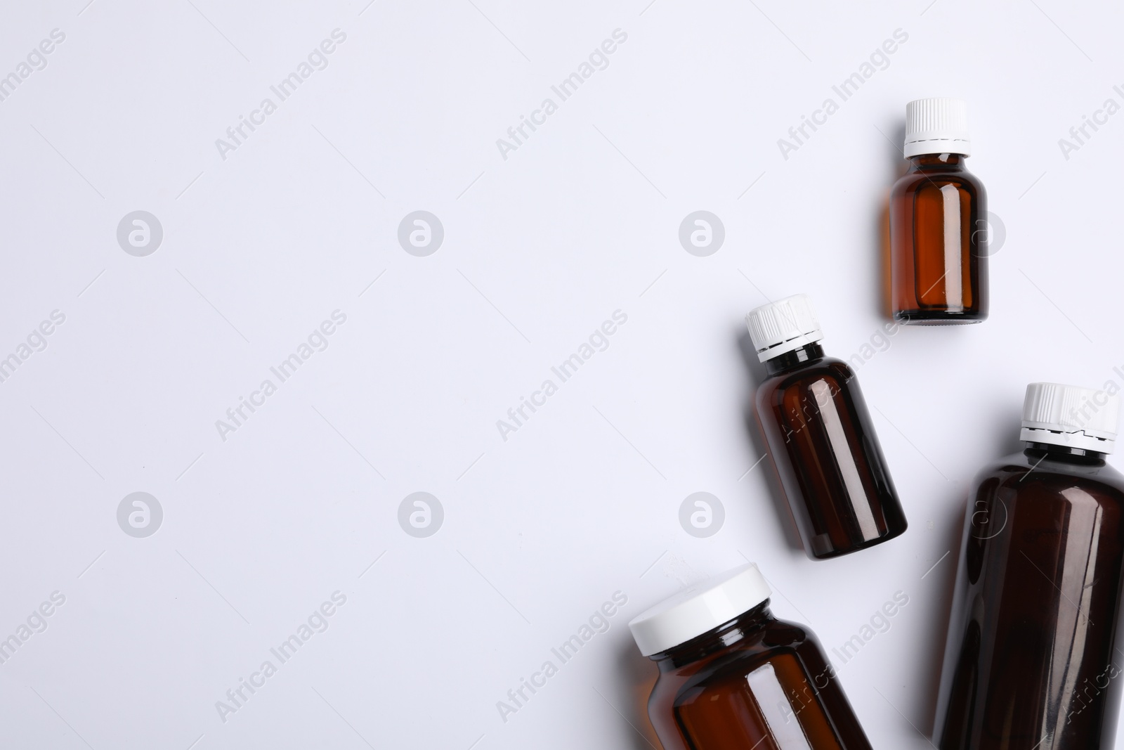 Photo of Medical bottles with medicine on white background, top view. Space for text