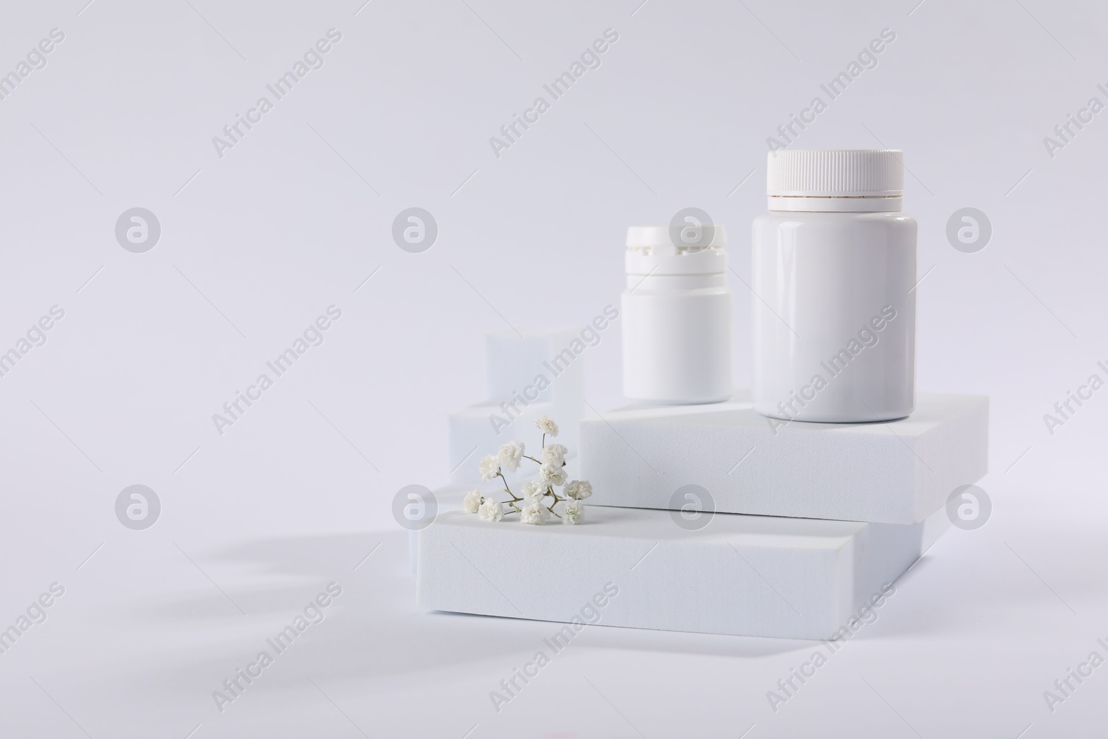 Photo of Plastic medical bottles and flowers on white background