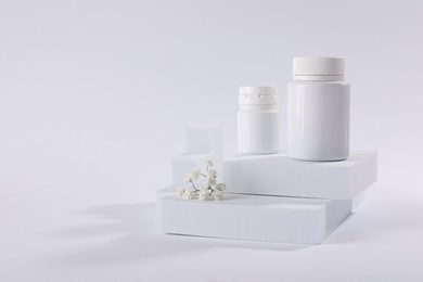 Photo of Plastic medical bottles and flowers on white background