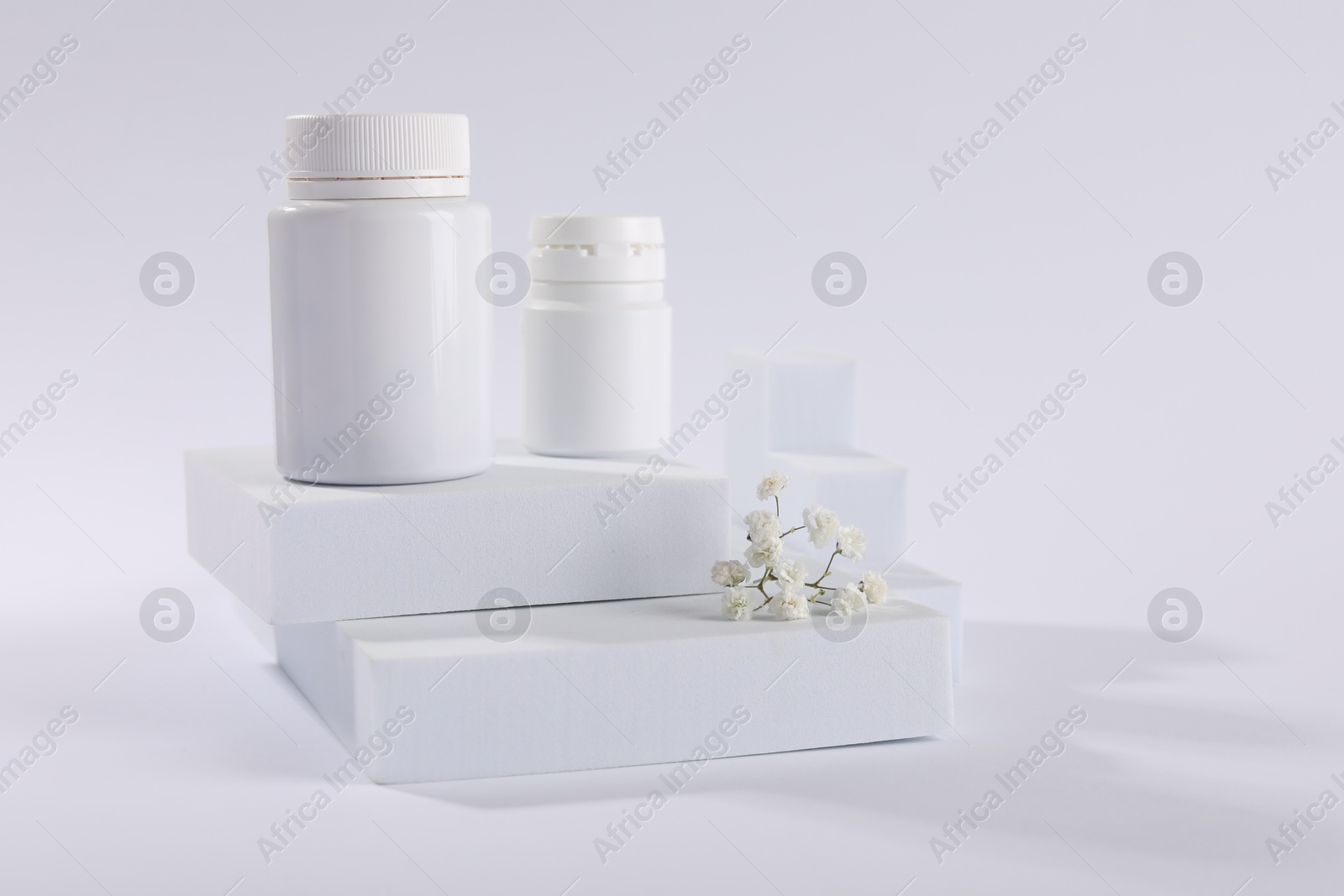 Photo of Plastic medical bottles and flowers on white background