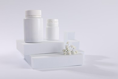 Photo of Plastic medical bottles and flowers on white background