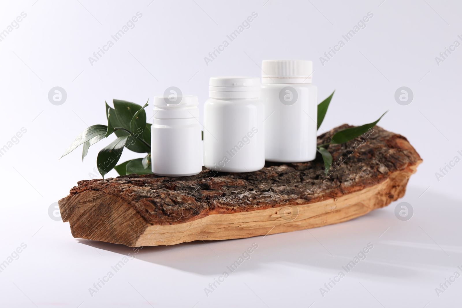 Photo of Plastic medical bottles, green leaves and snag on white background