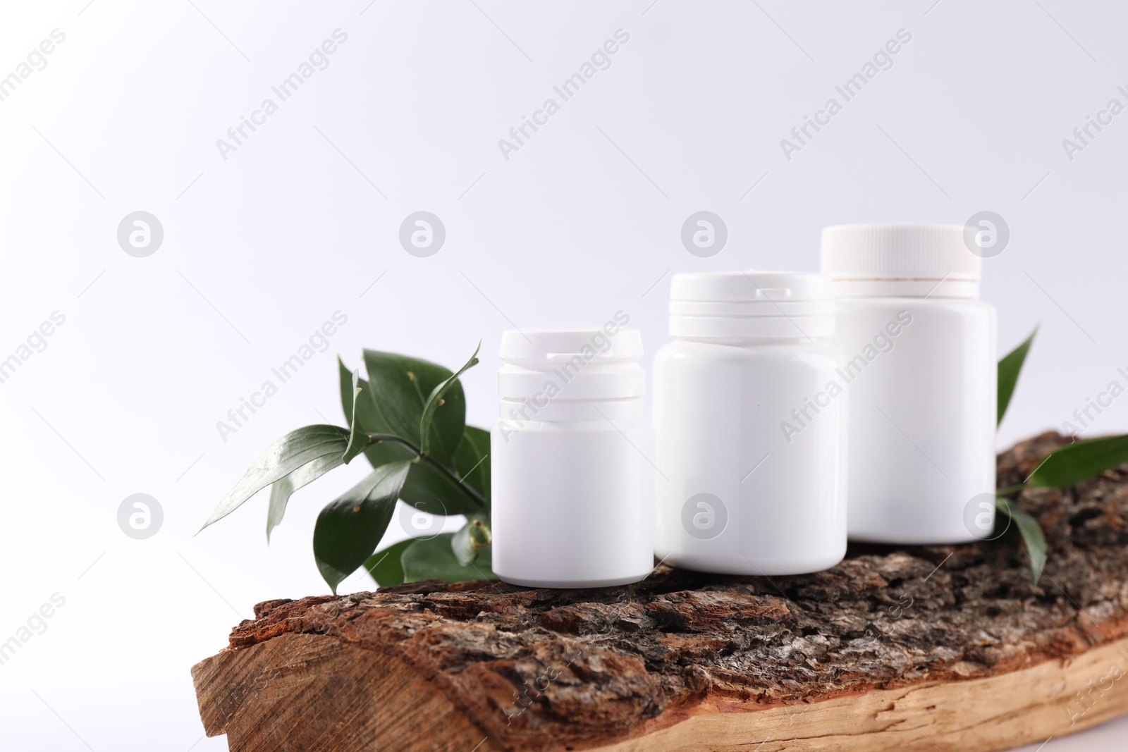 Photo of Plastic medical bottles, green leaves and snag on white background, closeup