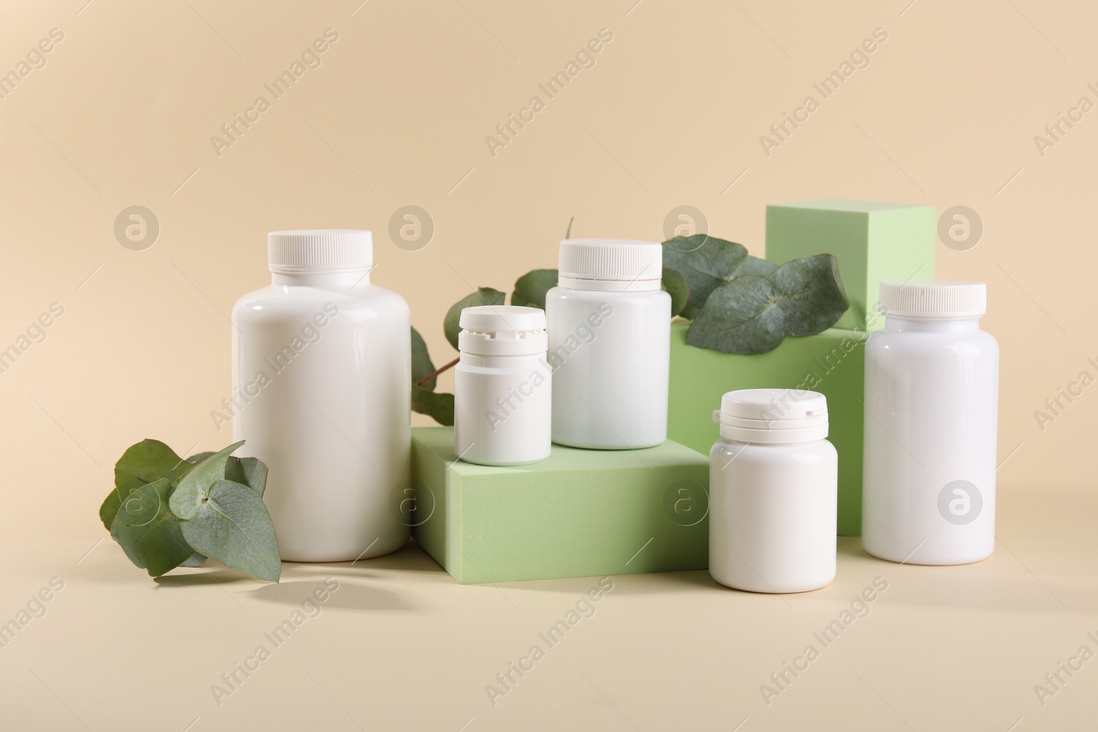 Photo of Plastic medical bottles, eucalyptus leaves and podiums on beige background