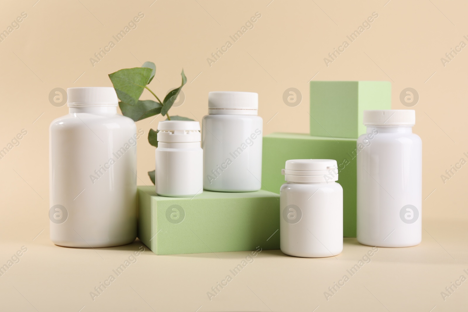 Photo of Plastic medical bottles, eucalyptus leaves and podiums on beige background