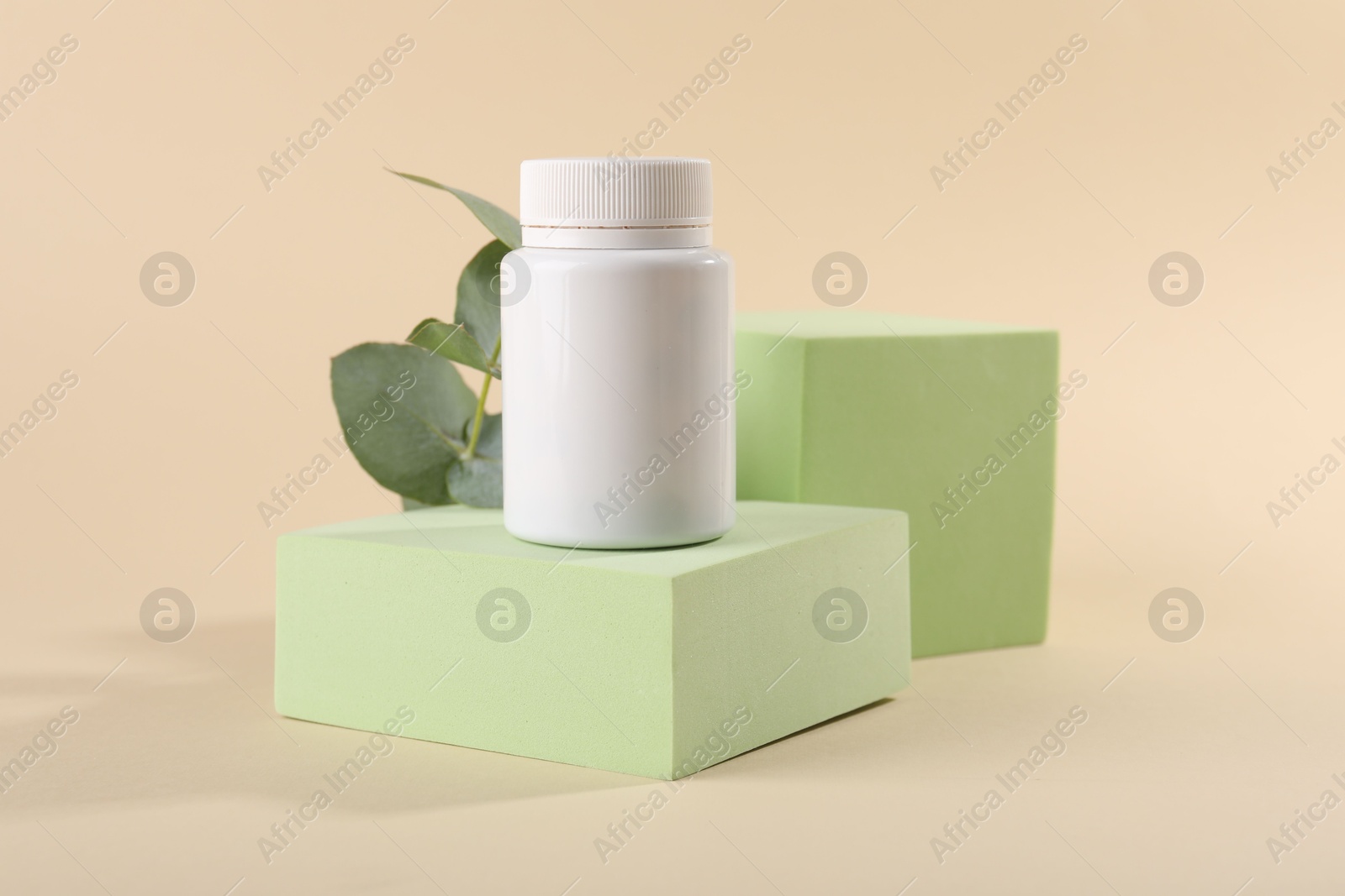 Photo of Plastic medical bottle, eucalyptus leaves and podiums on beige background