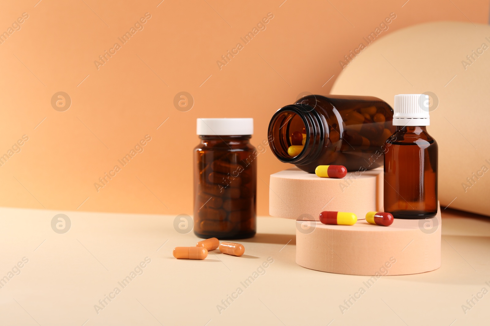 Photo of Medical bottles with medicine and podiums on beige background, space for text