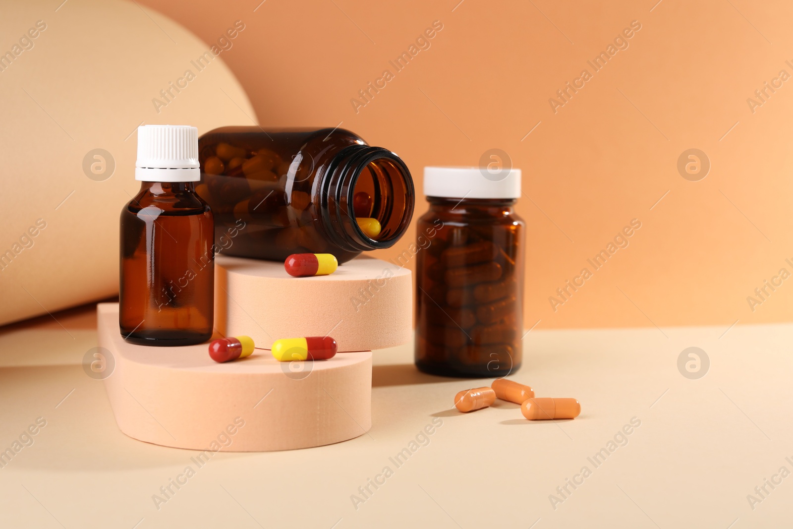 Photo of Medical bottles with medicine and podiums on beige background