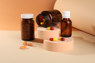 Photo of Medical bottles with medicine and podiums on beige background