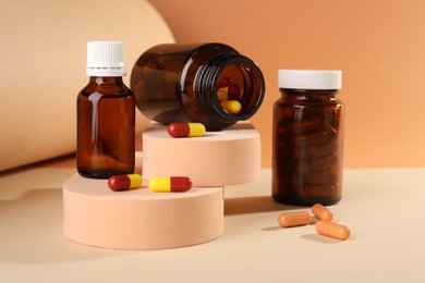 Photo of Medical bottles with medicine and podiums on beige background