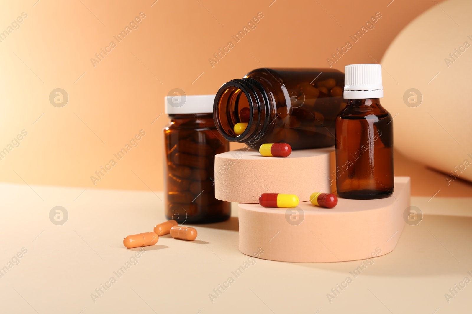 Photo of Medical bottles with medicine and podiums on beige background