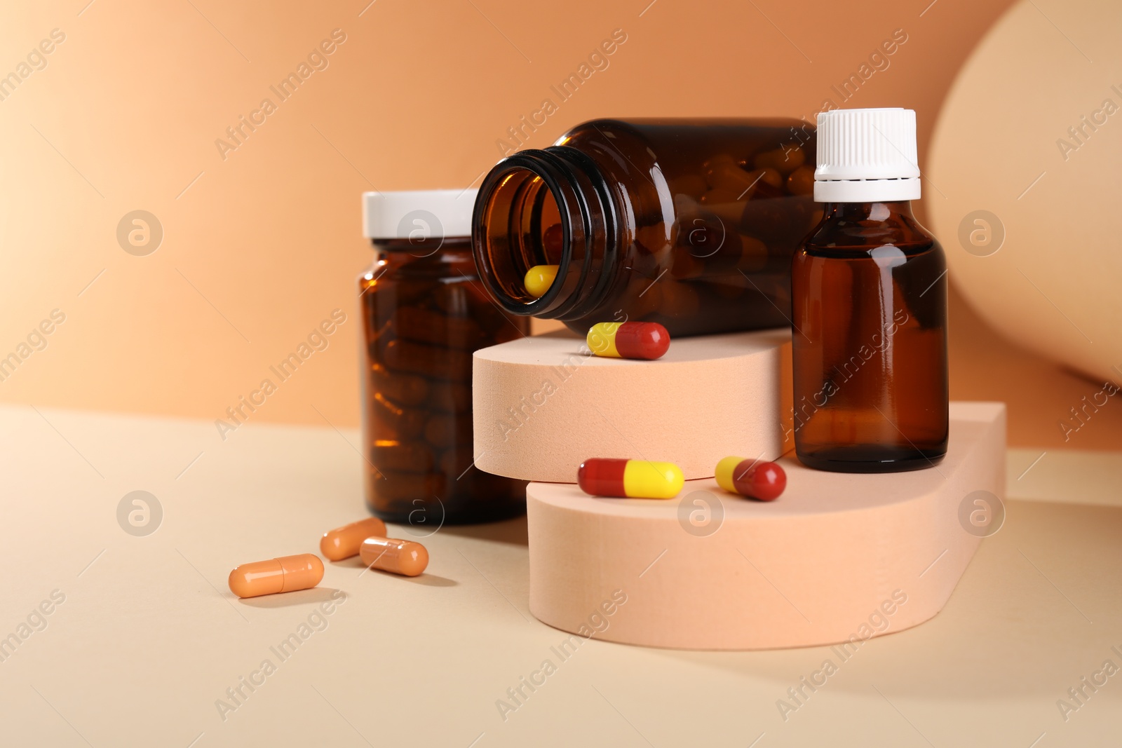 Photo of Medical bottles with medicine and podiums on beige background