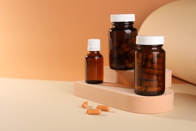 Photo of Medical bottles with medicine and podiums on beige background, space for text