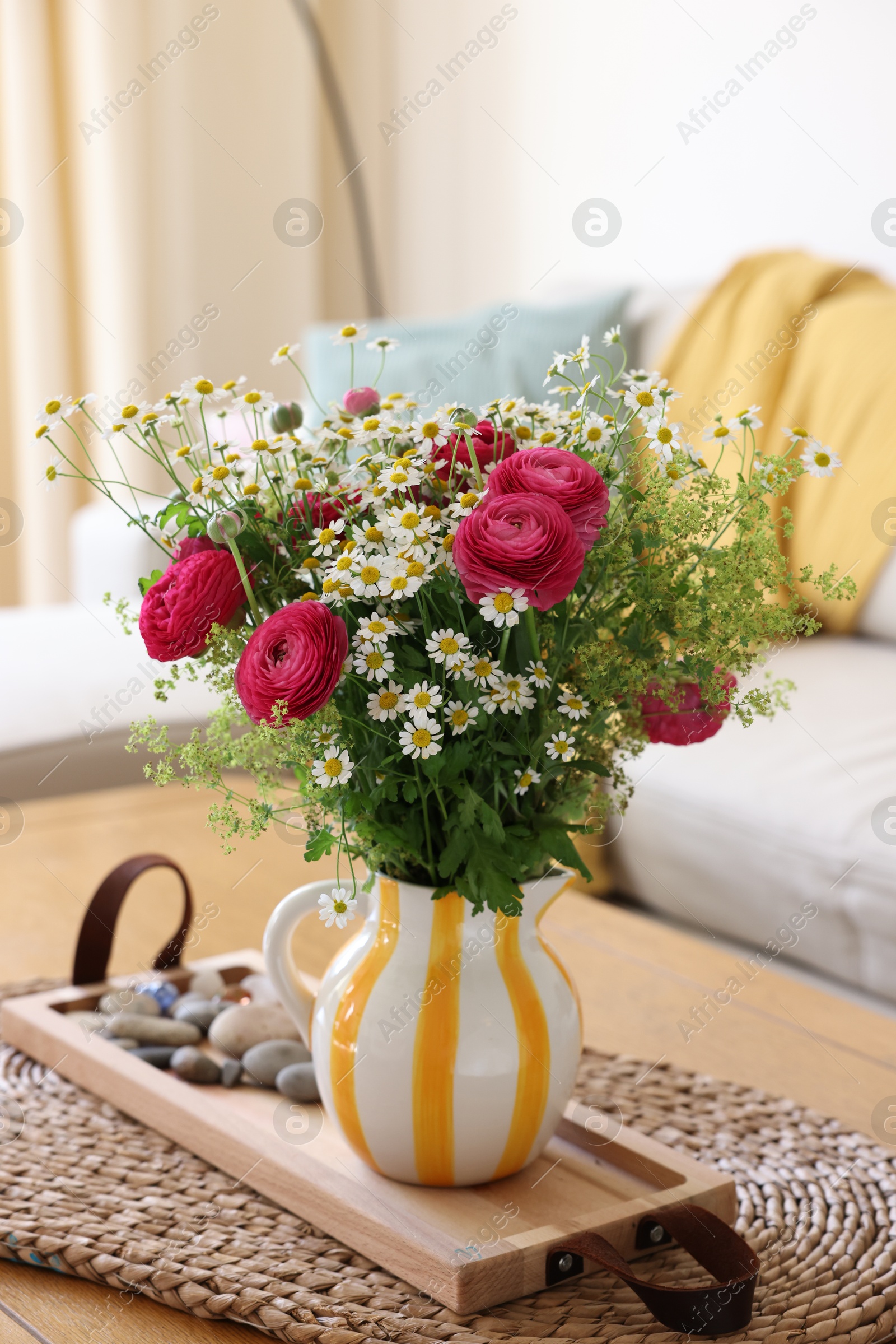 Photo of Beautiful ranunculus flowers and chamomiles in vase on table indoors