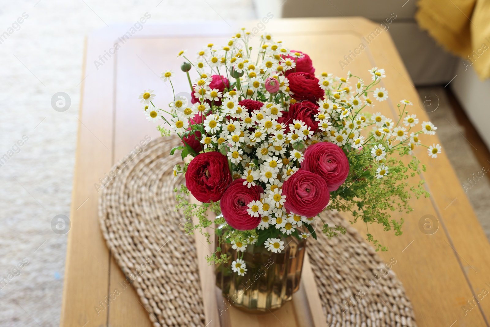 Photo of Beautiful ranunculus flowers and chamomiles in vase on table indoors