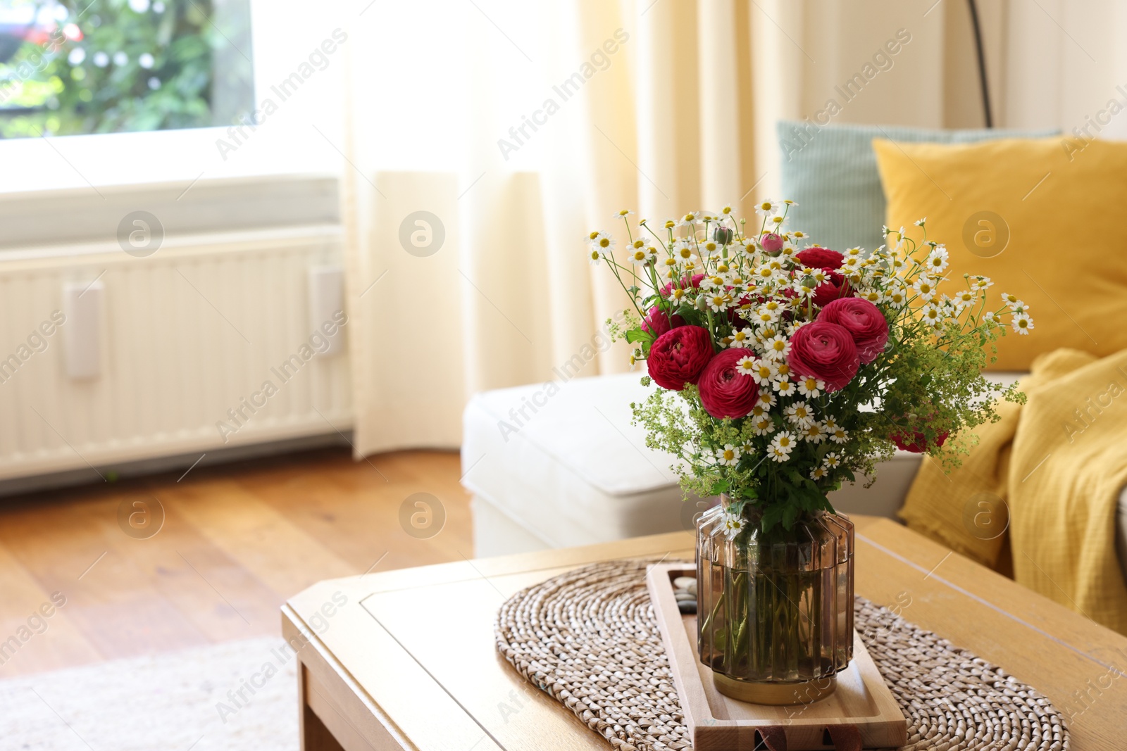 Photo of Beautiful ranunculus flowers and chamomiles in vase on table indoors