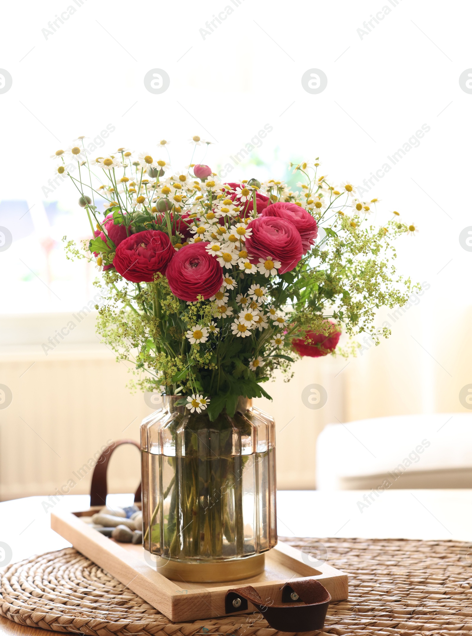 Photo of Beautiful ranunculus flowers and chamomiles in vase on table indoors