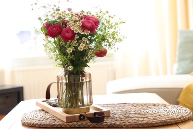 Photo of Beautiful ranunculus flowers and chamomiles in vase on table indoors