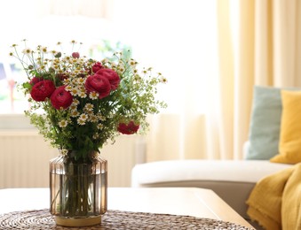 Photo of Beautiful ranunculus flowers and chamomiles in vase on table indoors