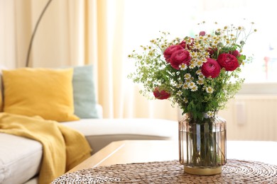 Photo of Beautiful ranunculus flowers and chamomiles in vase on table indoors