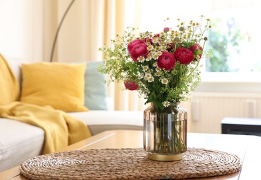 Photo of Beautiful ranunculus flowers and chamomiles in vase on table indoors