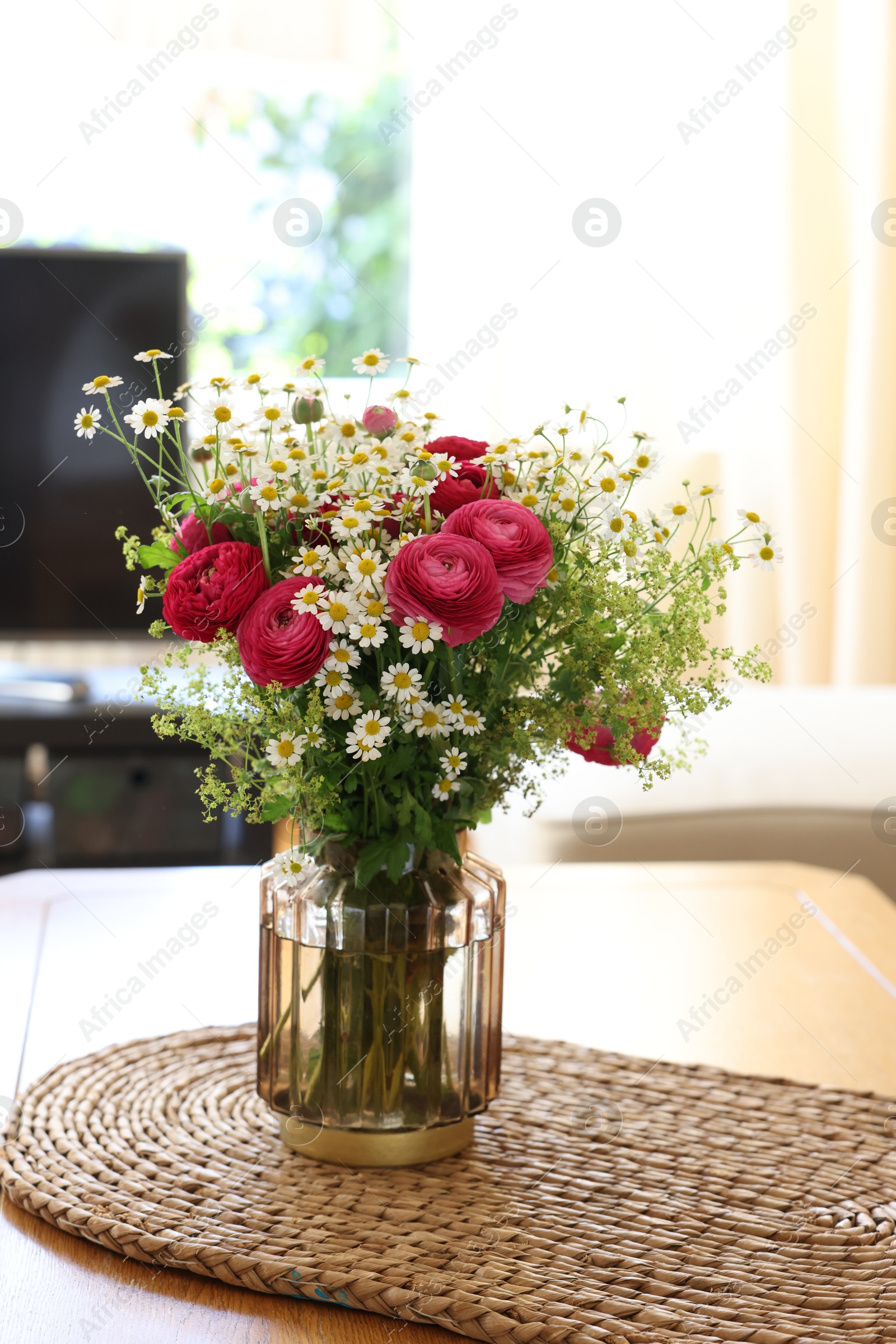 Photo of Beautiful ranunculus flowers and chamomiles in vase on table indoors