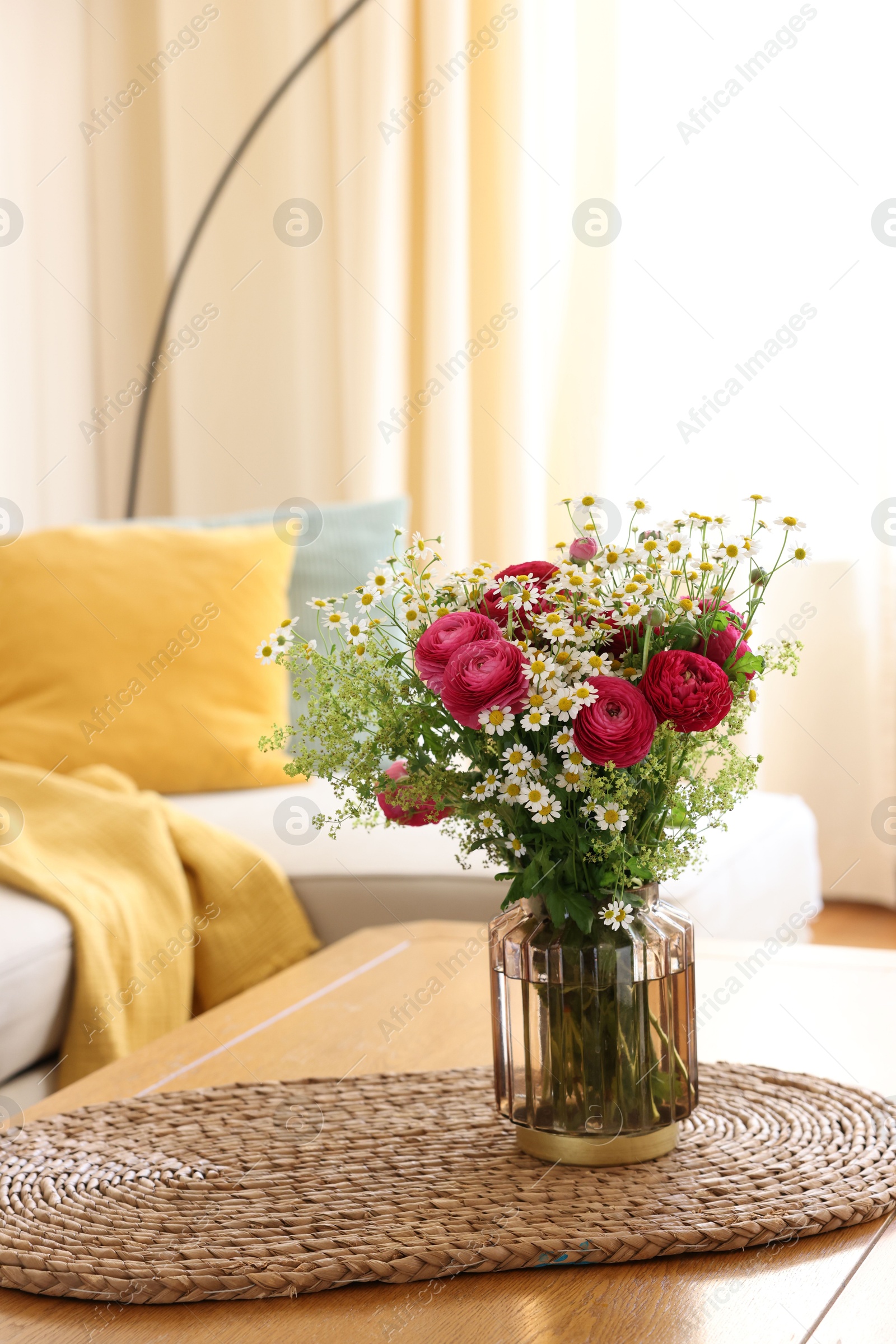 Photo of Beautiful ranunculus flowers and chamomiles in vase on table indoors