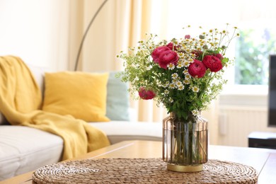 Photo of Beautiful ranunculus flowers and chamomiles in vase on table indoors