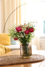 Photo of Beautiful ranunculus flowers and chamomiles in vase on table indoors