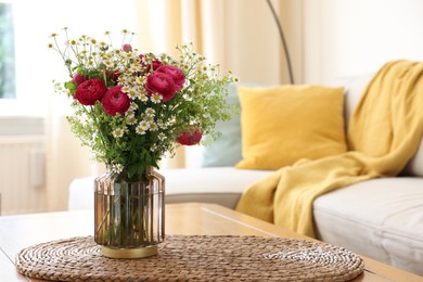 Photo of Beautiful ranunculus flowers and chamomiles in vase on table indoors